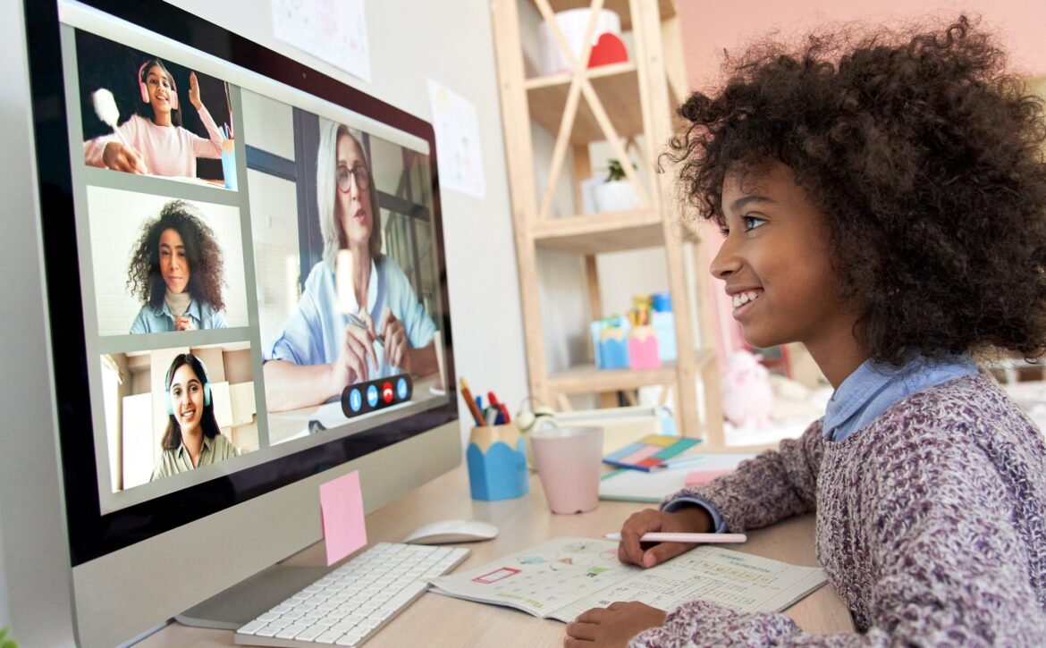 Cute african kid child girl distance learning during virtual distance online class on video conference call with teacher, tutor and school children group studying at home. Elearning class on computer.